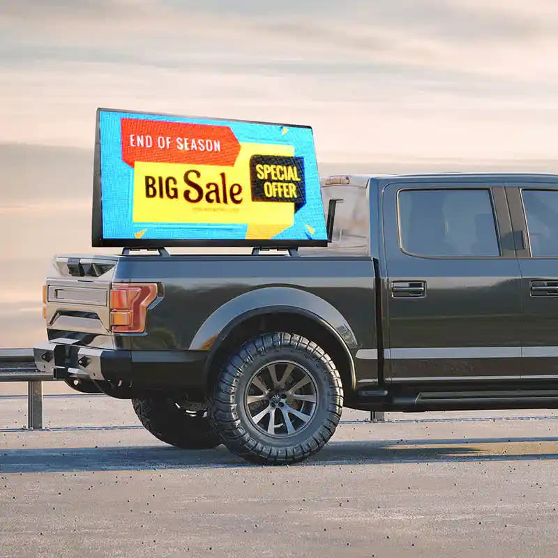 Truck with a digital display showing a sale advertisement on a road.