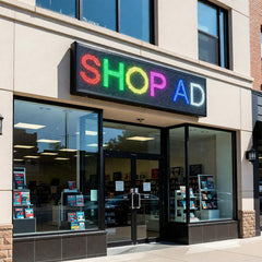 Storefront with a colorful LED sign displaying 'SHOP AD' above glass doors.