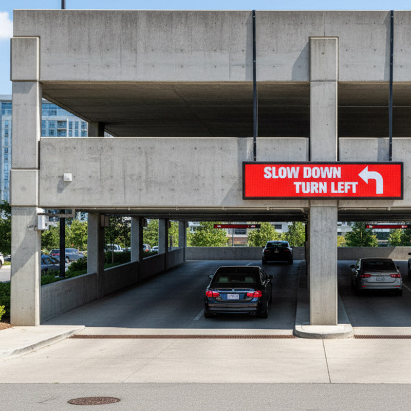 Red traffic sign on a concrete overpass warning drivers to slow down and turn left.
