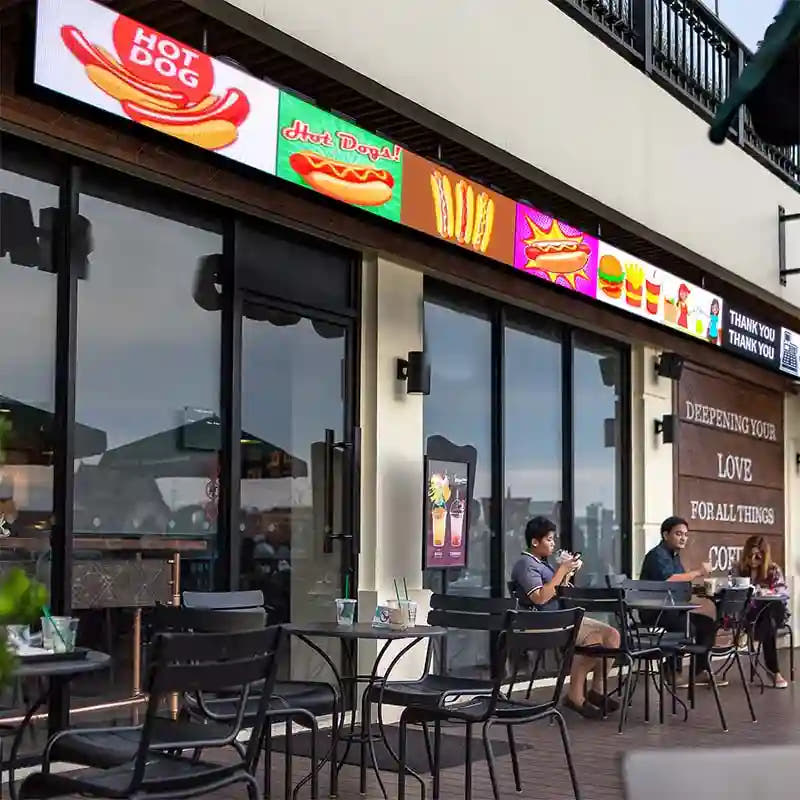 Outdoor seating area of a restaurant with a colorful signboard above the entrance.