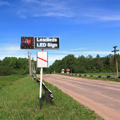LED sign on a rural road with trees and blue sky in the background
