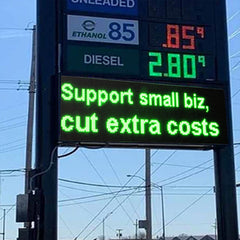 Gas station sign with fuel prices and a message encouraging support for small businesses.
