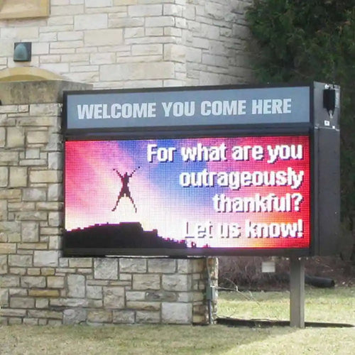 Digital sign with a question about thankfulness in front of a stone building.