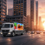 White truck with digital display showing food graphics on a city street at sunset.