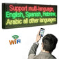 Person using a smartphone to control an LED sign displaying multiple languages.