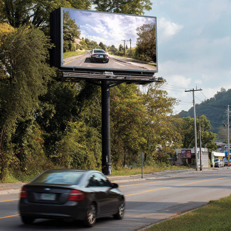 An LED billboard displaying a scenic road view on a rural highway