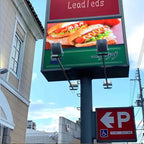 Digital billboard displaying a hotdog graphic with a clear blue sky in the background