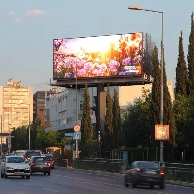LED Billboard displaying a scenic image of flowers on a city street with cars and buildings Main image