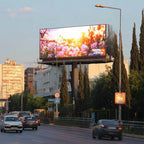LED Billboard displaying a scenic image of flowers on a city street with cars and buildings