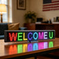LED sign displaying 'WELCOME U' on a table in a room with furniture and decor.